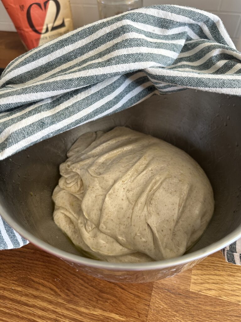 Sourdough bread dough resting in a bowl covered with a kitchen towel during fermentation.